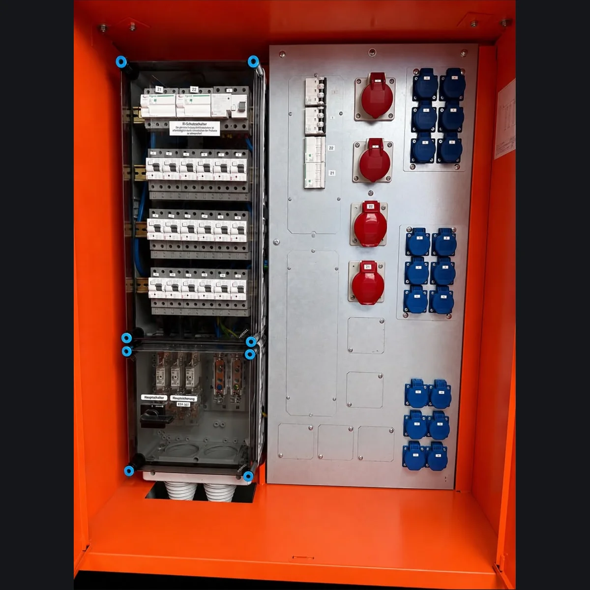 Innenansicht eines Stromverteilers mit Hauptsicherung 63A, roten CEE-Steckdosen und zahlreichen blauen Schuko-Steckdosen
